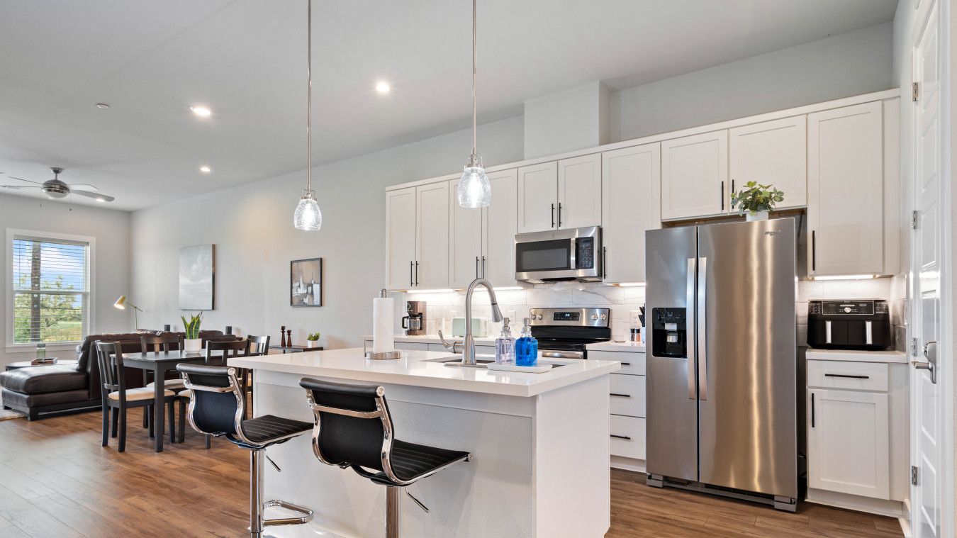 A modern kitchen with white cabinets, stainless steel appliances, and a central island with bar stools.