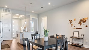 A modern kitchen with white cabinets, a central island, and pendant lighting.