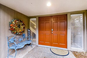 A wooden door with a mailbox, a bench, and a decorative wreath.
