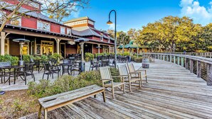 Une terrasse en bois avec des sièges d’extérieur et un bâtiment à la façade rouge.
