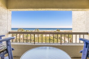 A balcony with a view of the beach and ocean.