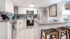 Une cuisine moderne avec des meubles blancs, des appareils en acier inoxydable et un plan de travail en granit.