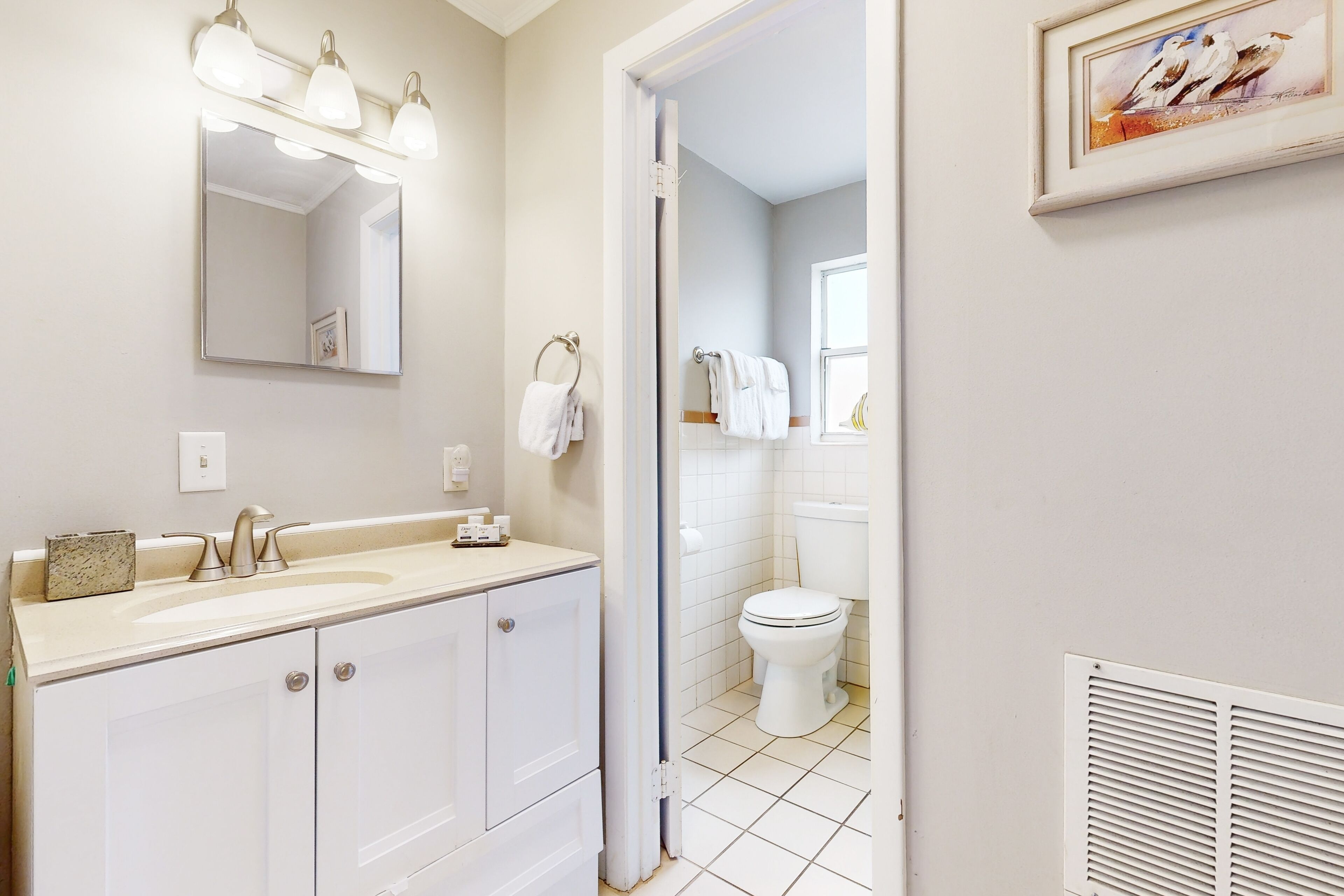 Une salle de bain avec un lavabo, un miroir et des toilettes.