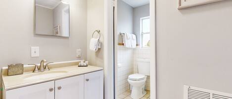 Une salle de bain avec un lavabo, un miroir et des toilettes.