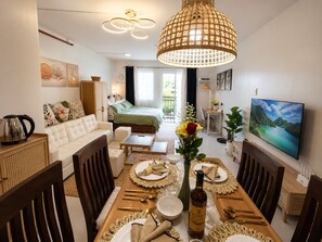 Une salle à manger bien éclairée, avec une table dressée pour le repas, un canapé et un lit en arrière-plan.