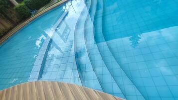 A swimming pool with a curved edge and a wooden deck in the foreground.