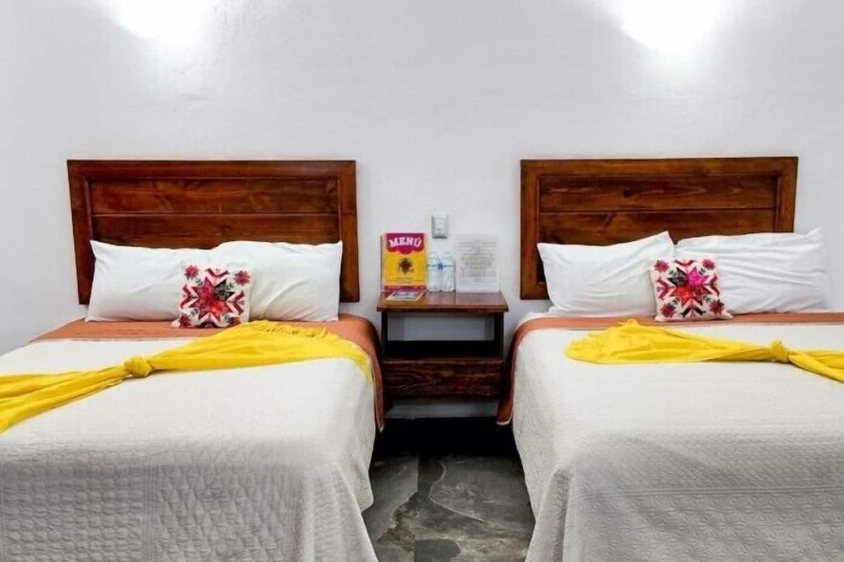 Two single beds with wooden headboards, white bedding, and yellow accents.