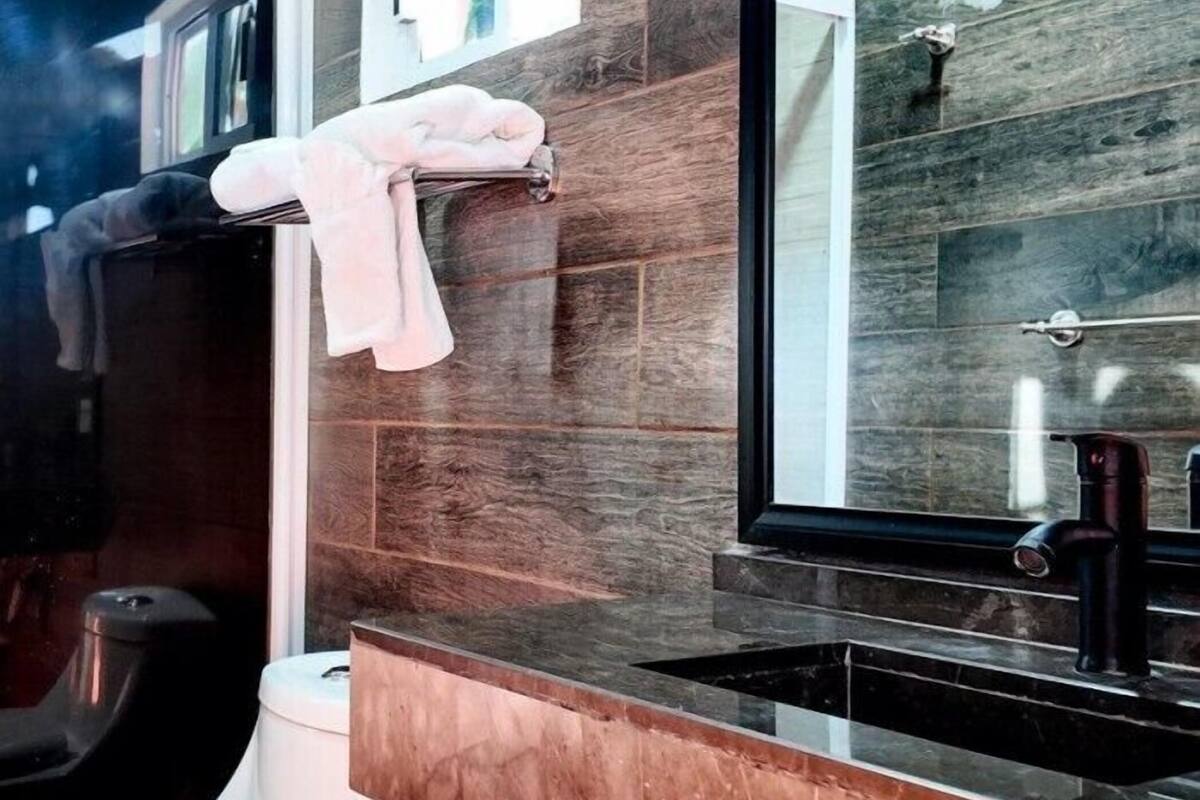 A modern bathroom with a black sink, a mirror, and a towel rack.