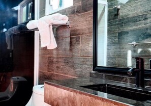 A modern bathroom with a black sink, a mirror, and a towel rack.