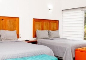 Habitación de hotel con dos camas, cabeceros de madera y una ventana con persianas.
