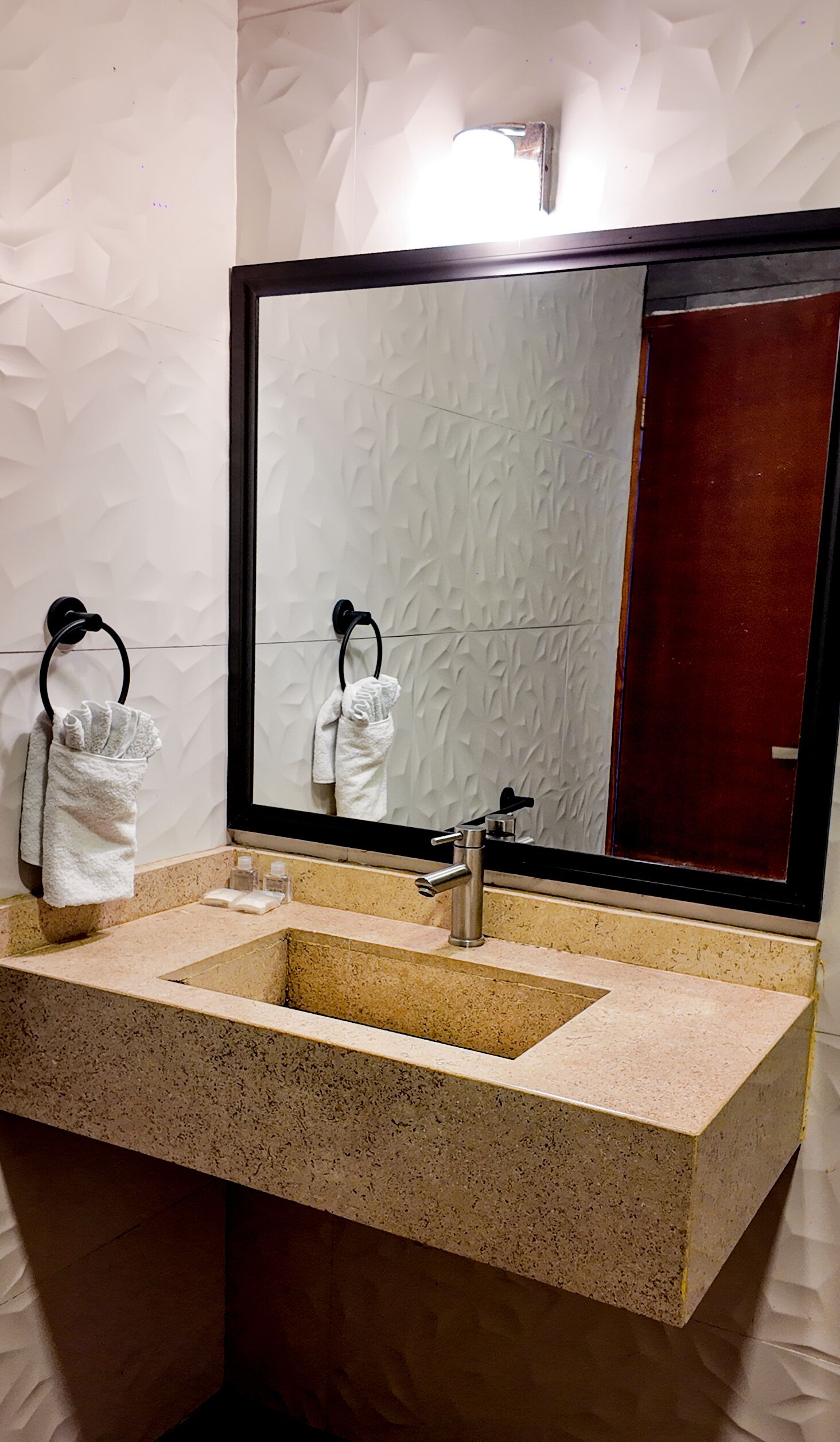 A bathroom with a large mirror, two sinks, and towels hanging on towel rings.