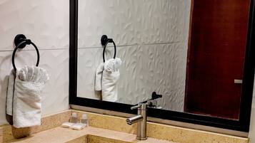 A bathroom with a large mirror, two sinks, and towels hanging on towel rings.
