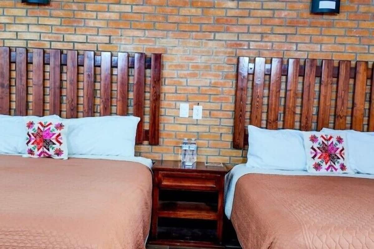 A double room with two beds, each with a wooden headboard, a small wooden nightstand, and a decorative pillow.