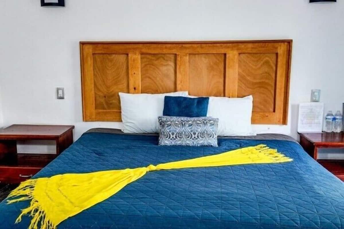 A bed with a blue quilt, a wooden headboard, and decorative pillows.