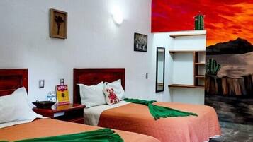 Una habitación de hotel con dos camas, una mesita de noche, un espejo y un cuadro de un paisaje desértico.