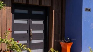 A building with a dark wooden door and a blue wall. There is a sign that reads "SUITE" on the wall.