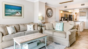 A living room with a beige sofa, a coffee table, and a painting of a seascape.
