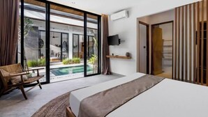A modern bedroom with a large bed, a view of an outdoor swimming pool, and a sliding glass door leading to a balcony. - Villa Ornella by BaliSuperHost (Bali)