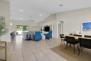 Un salón espacioso con una mesa de comedor, sofás y un televisor.