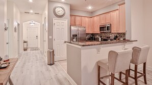 A modern kitchen with wooden cabinets, stainless steel appliances, and a breakfast bar. - Elegant waterfront condo with central AC, balcony, and shared pools & hot tubs (Palm Coast)