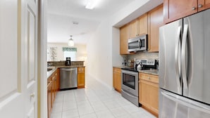 A modern kitchen with stainless steel appliances, wooden cabinets, and a tiled floor.