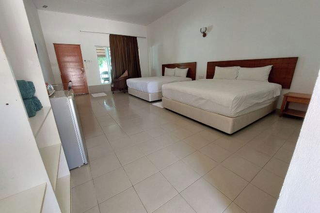A hotel room with a large bed, a smaller bed, a desk, and a chair.