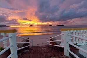 A wooden deck leading to a beach with a railing, overlooking the sea and a sunset. - Nazrat Residence (Langkawi)