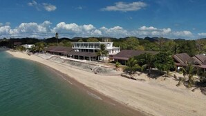 A beachfront property with a large building, a sandy beach, and lush greenery. - Nazrat Residence (Langkawi)