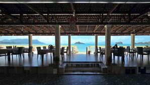 An outdoor dining area with a view of the beach and mountains. - Nazrat Residence (Langkawi)