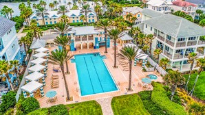An aerial view of a resort with a central swimming pool, multiple buildings, and lush landscaping. - Coastal Gem on the Golf Course w/ Shared Pool, & Beach Access - Dog-Friendly (Palm Coast)