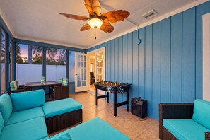 A sunroom with a ceiling fan, a foosball table, and blue walls.