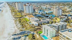 Una zona urbana costera con rascacielos, una playa y una piscina.