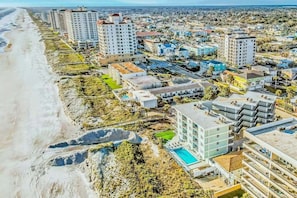 A coastal urban area with high-rise buildings, a beach, and a swimming pool. - Polished oceanfront condo with pool access, private balcony & washer/dryer (Jacksonville Beach)