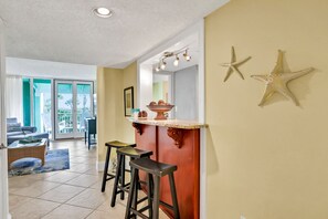 A kitchen with a bar area, two stools, and starfish decorations on the wall.