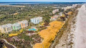 Une vue aérienne d’une zone côtière avec de nombreux bâtiments, une plage et une piscine.