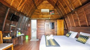 A wooden cabin room with a bed, a desk, and a television. - Sunny Point Penida (Bali)