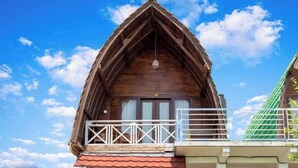 A wooden chalet with a balcony and a steeply pitched roof. - Sunny Point Penida (Bali)
