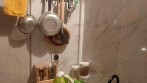 A kitchen with a marble backsplash, a kettle, a coffee maker, and various utensils hanging above the counter. - Sunny Point Penida (Bali)