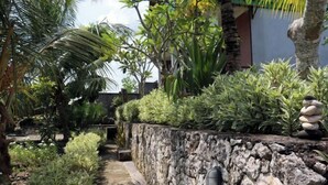 A stone wall with a small garden and a pathway. - Sunny Point Penida (Bali)