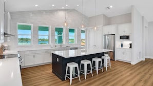 A modern kitchen with a large island, white cabinetry, and a view of a swimming pool. - Brand new oceanfront home with private hot tub,outdoor shower and grill (Flagler Beach)