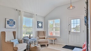 A spacious living room with two armchairs, a coffee table, and a door with a view.