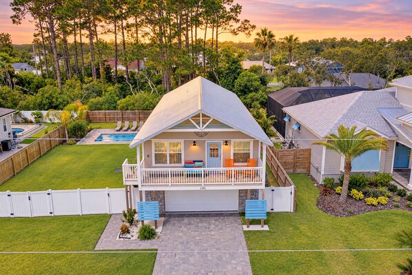 A two-story house with a balcony, a swimming pool, and a well-maintained lawn.