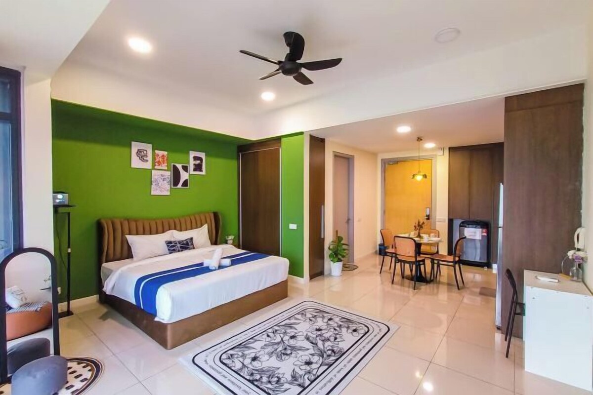 A modern hotel room with a bed, a dining area, and a kitchenette.