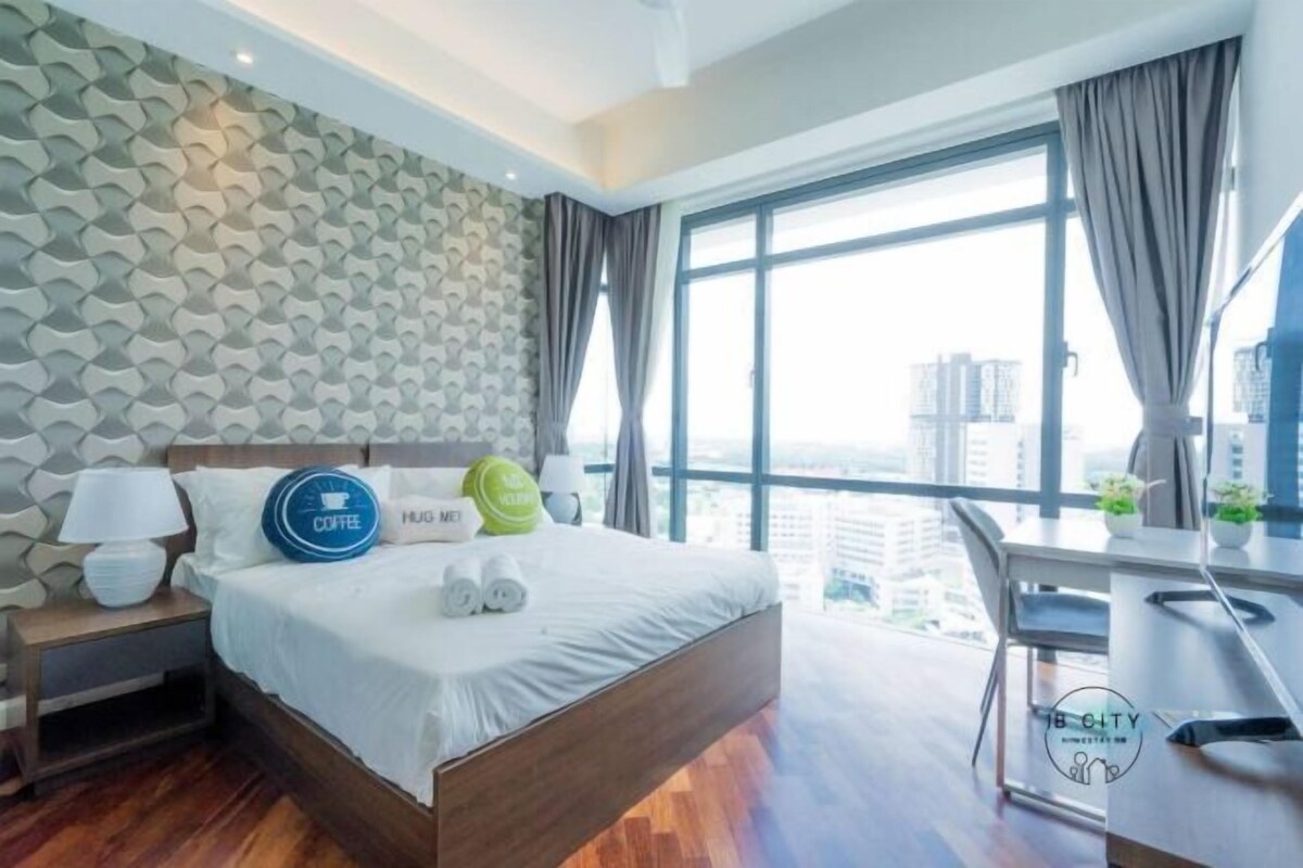 A modern hotel room with a large bed, a desk, and a view of the city.