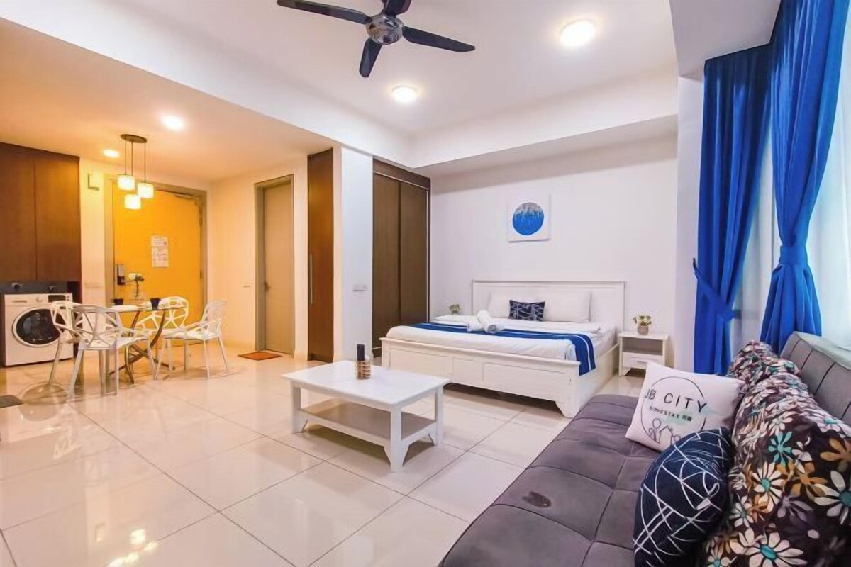A modern hotel room with a bed, a sofa, a dining area, and a ceiling fan.