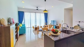 A modern kitchen with a central island, a dining area with chairs and a table, and a living area with a sofa and curtains. - Grand Medini Suites by RR JBcity (Iskandar Puteri)
