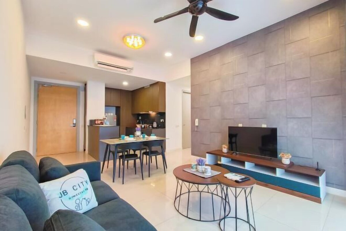 A modern living room with a sofa, a coffee table, a TV, and a dining area with chairs and a table.