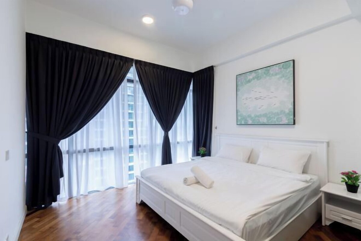 A bedroom with a bed, a nightstand, a window with curtains, and a painting on the wall.