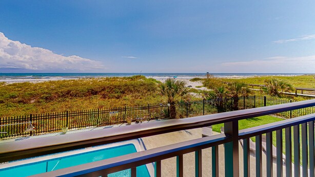 A pool area with a view of the beach and ocean.