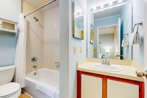 A bathroom with a bathtub, toilet, sink, and a mirror with lights. - Ocean-view townhome with balcony & W/D - walk to beach - dog-friendly (Jacksonville Beach)
